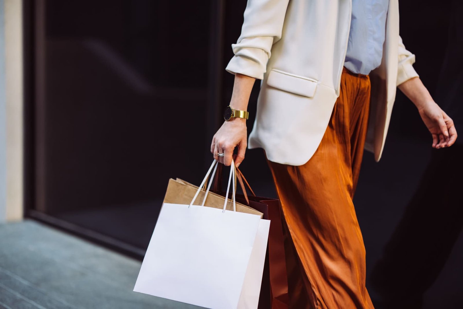 Shopper carrying bags near a downtown storefront